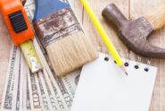 An overhead view shows money, a calculator, a notebook, and tools to plan and budget for home remodeling.