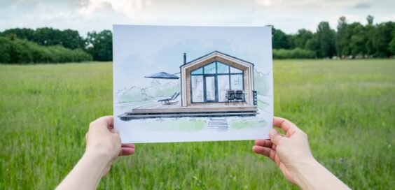 A person holding a blueprint image in front of them with both arms. There is an empty field behind the image.