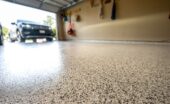 Low-angle and close-up view of a polished garage floor with an SUV visible in the driveway beyond the open door.