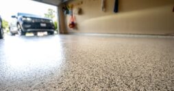 Low-angle and close-up view of a polished garage floor with an SUV visible in the driveway beyond the open door.