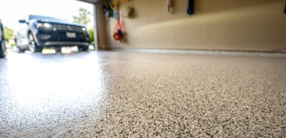 Low-angle and close-up view of a polished garage floor with an SUV visible in the driveway beyond the open door.