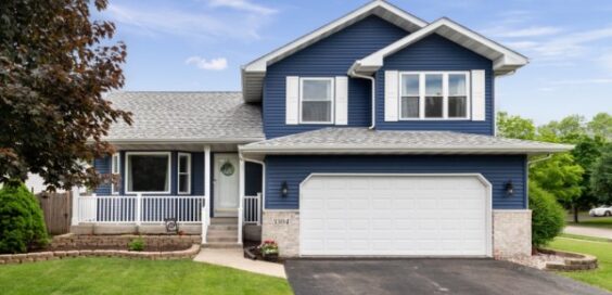 The exterior of the house with a small porch. The house's siding is blue, with a gray roof and white accents.