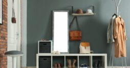The mudroom of a home with grey and red brick walls, storage for shoes, a coat rack, a mirror, and hardwood floors.