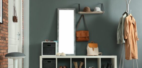 The mudroom of a home with grey and red brick walls, storage for shoes, a coat rack, a mirror, and hardwood floors.
