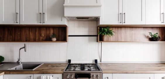 Bright contemporary kitchen featuring white cabinetry, open wood shelving, a gas stove, and minimalist decor.