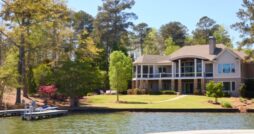 A waterfront home sits among mature trees with a landscaped lawn and private dock extending into the lake.