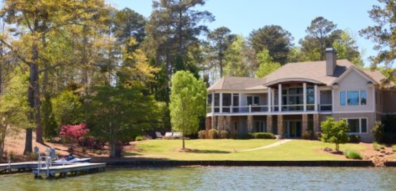 A waterfront home sits among mature trees with a landscaped lawn and private dock extending into the lake.