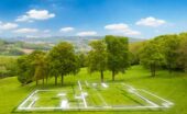 An open plot of land with a few trees near the back. There is a floating outline of a house that is to be built on the land.